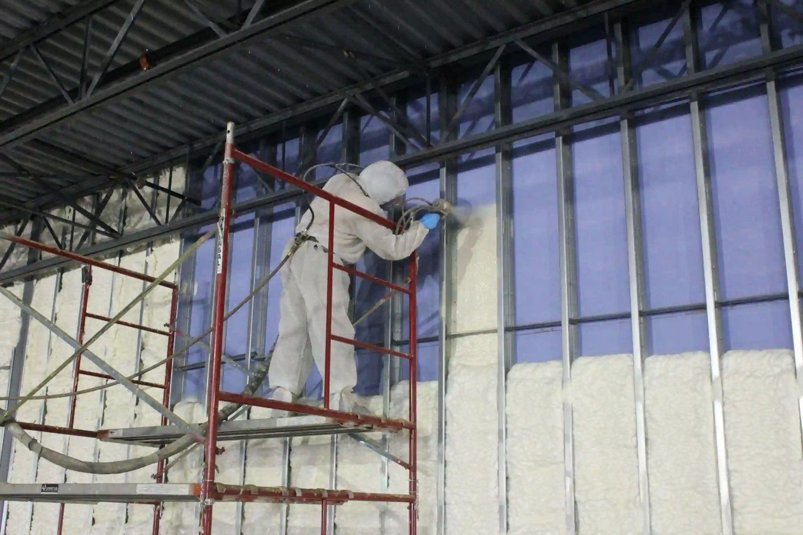 Technician spray foaming the wall of a commercial building
